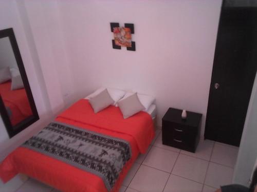 a bedroom with a red bed and a mirror at La Maison de Lydia in Nazca