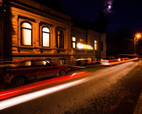 a city street with cars driving past a building at night at Hotel 5 Continents in Craiova