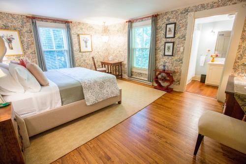 a bedroom with a bed and wooden floors and windows at Gay Street Inn in Washington, Virginia