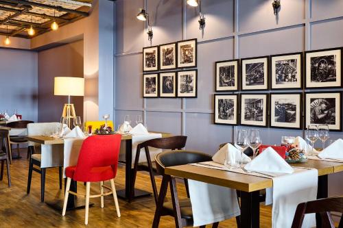 アラドにあるibis Styles Aradの壁に絵画が飾られたテーブルと椅子のあるレストラン