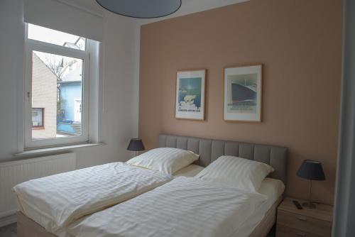 a bedroom with a bed with white sheets and two windows at Hotel Stadt Cuxhaven in Cuxhaven