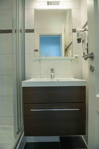 a bathroom with a sink and a mirror and a shower at Hotel Stadt Cuxhaven in Cuxhaven