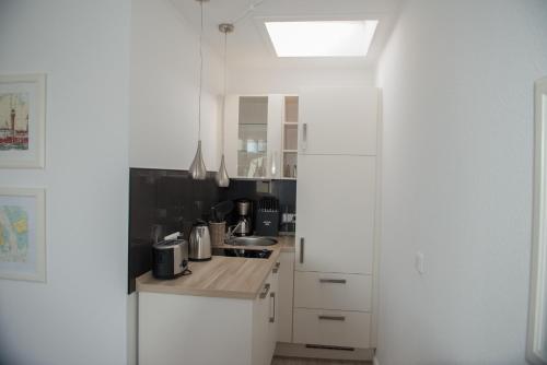 a kitchen with white cabinets and a sink at Hotel Stadt Cuxhaven in Cuxhaven