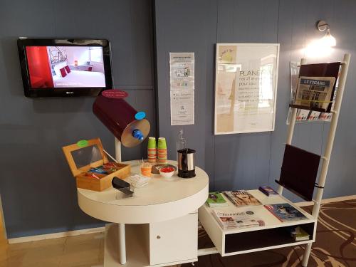 アルルにあるibis Styles Arles Palais des Congrèsのテーブルと壁にテレビが掛かっている部屋