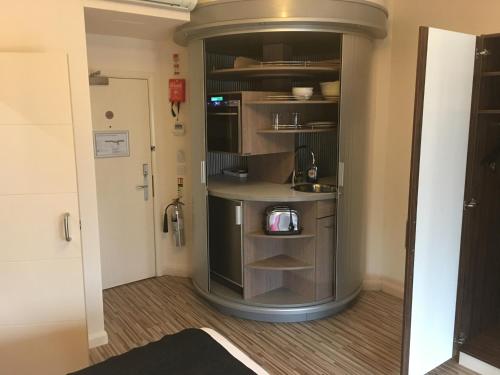 a room with a kitchen with a sink and shelves at Simply Rooms & Suites in London