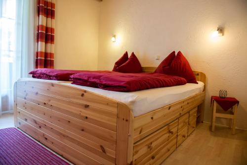 1 dormitorio con cama de madera y almohadas rojas. en FEWO Silberberg TOP 4 en Alpbach