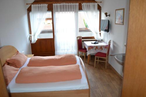 a bedroom with a bed and a table and a sink at Gaestehaus Tagescafe Eckenfels in Ohlsbach