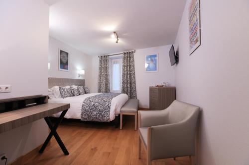 a small bedroom with a bed and a desk and a desk at Hôtel Restaurant Des Remparts in Chaumont
