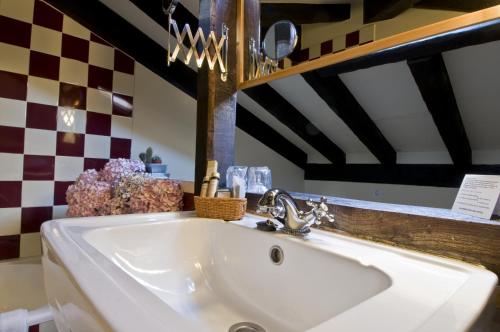 een witte wastafel in een badkamer met een geruite muur bij La Casona de Suesa in Suesa