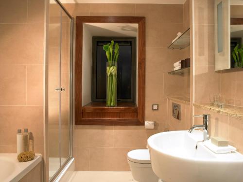 a bathroom with a sink and a toilet and a vase at Limerick Strand Hotel in Limerick