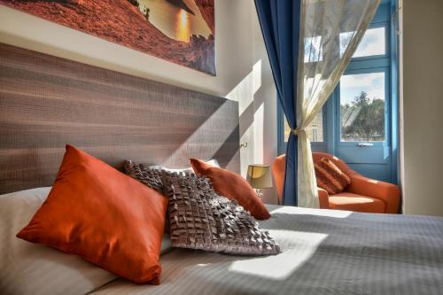 1 dormitorio con 1 cama con almohadas de color naranja y ventana en Central Suites St. Julian's, en San Julián
