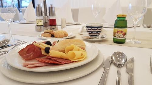 a table with a plate of food on a table at Hotel Garden Hill in Velika Gorica