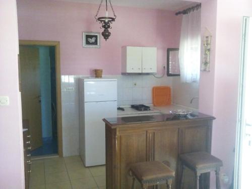 a kitchen with pink walls and a white refrigerator at Apartments Petko in Rogoznica