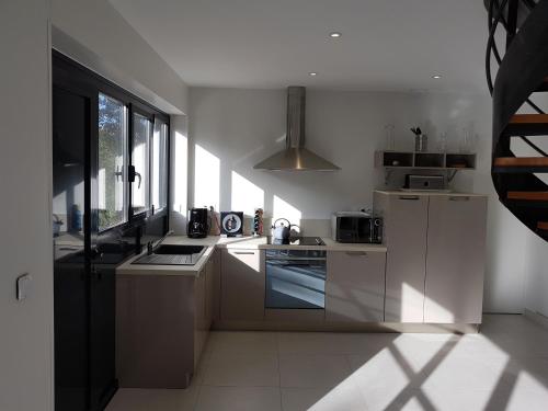 une cuisine avec des armoires blanches et un four à plaques de cuisson dans l'établissement Le lodge, à Vaux-sur-Mer