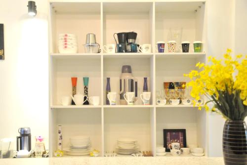 a shelf with cups and plates and a vase with flowers at La Me Villa Hoi An in Hoi An
