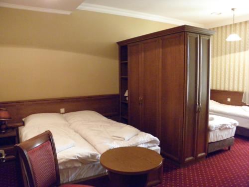 a bedroom with a bed and a cabinet and a table at Pałac Lucja BB in Zakrzów