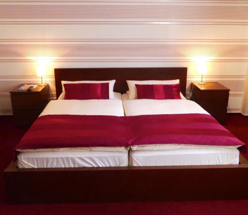 リューデスハイム・アム・ラインにあるホテル ツム ベーレンのベッドルーム1室(大型ベッド1台、赤い枕2つ付)