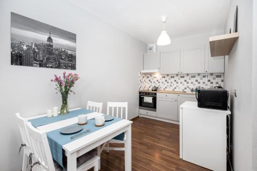 a white kitchen with a table and a kitchenette with a table and chairs at Apartament Gemini in Dzierżoniów