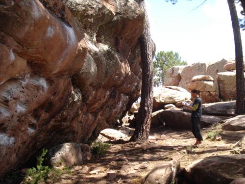 un homme debout devant un mur de roche dans l'établissement Camping-Bungalows Ciudad de Albarracín, à Albarracín