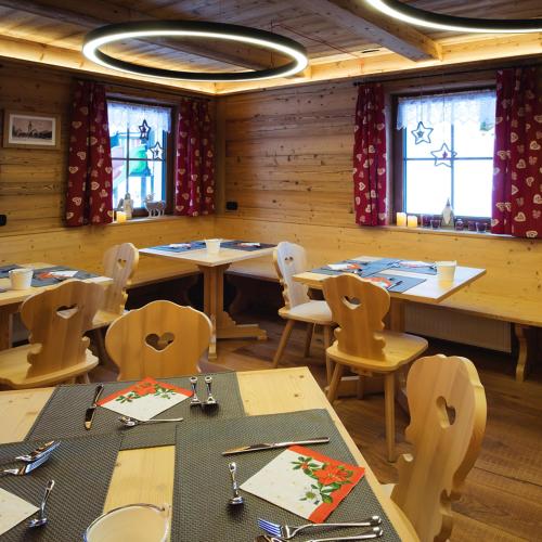 a dining room with tables and chairs and windows at Hotel Sogni D'Oro in Camporosso in Valcanale