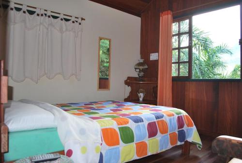 a bedroom with a bed with a colorful comforter at Pousada Arte de Viver in Lumiar