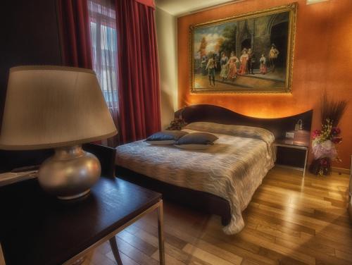 a bedroom with a bed with a lamp and a painting at La Grotta Hotel in Verona