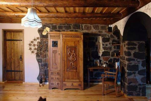 a room with a large wooden cabinet and a stone wall at Hye Aspet Հայ Ասպետ in Gyumri