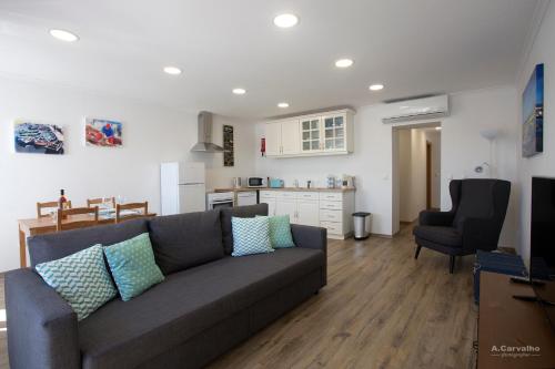 a living room with a gray couch and a kitchen at Casa das Sardinhas in Setúbal