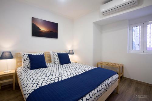Schlafzimmer mit einem blauen und weißen Bett und einem Fenster in der Unterkunft Casa das Sardinhas in Setúbal