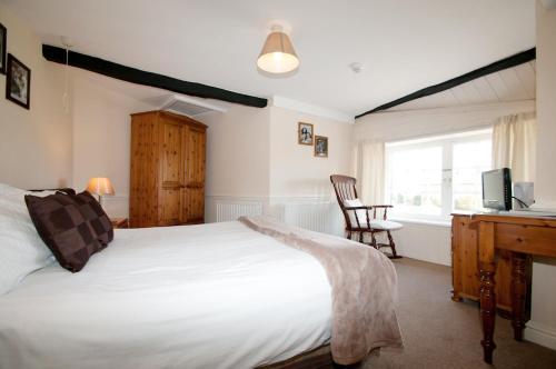 a bedroom with a bed and a desk and a window at Boot & Shoe Inn in Greystoke