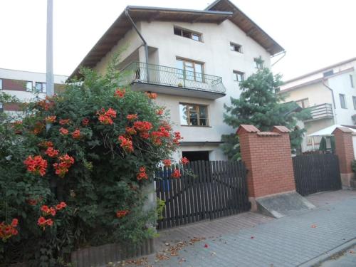 a white house with a black fence and red flowers at Apartament na Fatimskiej in Kraków