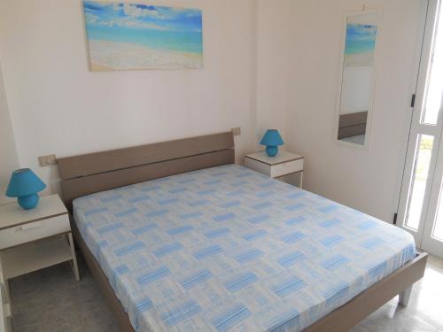 ガリポリにあるCasa vacanza Le Vele Gallipoli Baia Verdeのベッドルーム1室(ベッド1台、ナイトスタンド2台、ランプ2つ付)