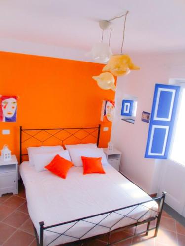 a bedroom with an orange headboard and a bed with red pillows at SalinArte in Santa Marina Salina