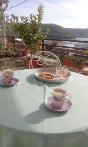 two cups of coffee and a plate of food on a table at Holiday Home Anna in Skradin