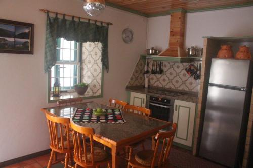 a kitchen with a table with chairs and a refrigerator at Casa dos Felicias in São Roque do Pico