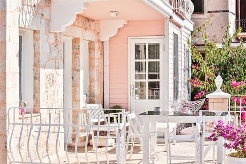 a pink house with a table and chairs on a porch at Club Çapa Hotel in Kas