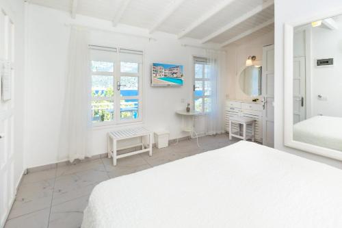a white bedroom with a bed and a mirror at Club Çapa Hotel in Kas