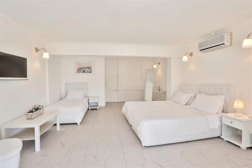 a white bedroom with a bed and a couch at Club Çapa Hotel in Kas