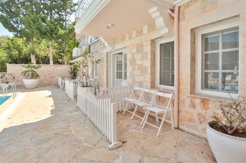 a patio with white chairs and a building at Club Çapa Hotel in Kas
