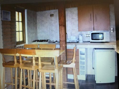 a kitchen with a table and chairs and a kitchen with a microwave at Cabañas Hosteria de Vilches in Vilches