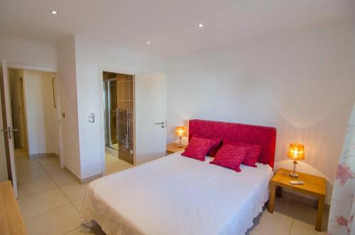 a bedroom with a large white bed with red pillows at Modern 2 Bed Apartment Vale do Lobo in Vale do Lobo