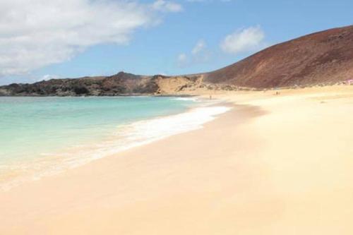 una playa de arena con el océano y una colina en Casa Armando, en Caleta de Sebo