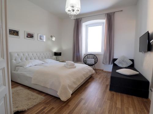 a white bedroom with a large bed and a window at Captain Emo City Apartments in Pula