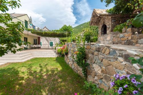 una pared de piedra frente a una casa con flores en Apartments Srdanovic, en Omiš