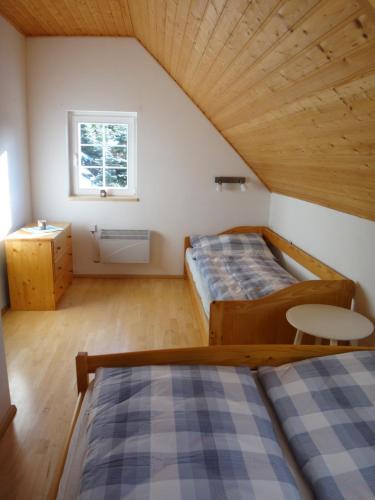 a attic bedroom with two beds and a window at Apartmán Na Zlatníku in Zlatá Olešnice