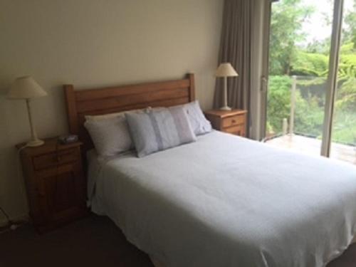 Un dormitorio con una gran cama blanca y una ventana. en Hahei Sea Vista (3 Bedroom House), en Hahei