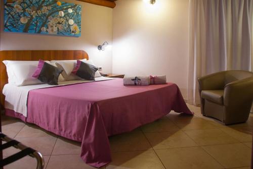 een slaapkamer met een bed met een roze deken en een stoel bij B&B Villa Eben Ezer in Avola