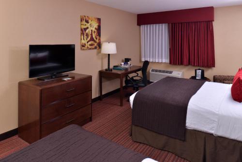 a hotel room with a bed and a desk with a television at Best Western Woodland Inn in Woodland