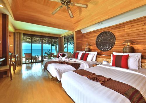 a bedroom with two beds in a room with the ocean at Sunset Park Resort And Spa - SHA Plus in Na Jomtien