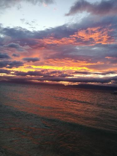 a sunset over the ocean with clouds in the sky at Ravenala Beach Bungalows in Moalboal